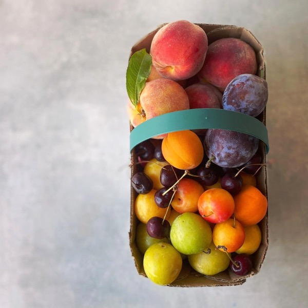 A basket of farm-fresh stone fruit from Bushel & Peck.