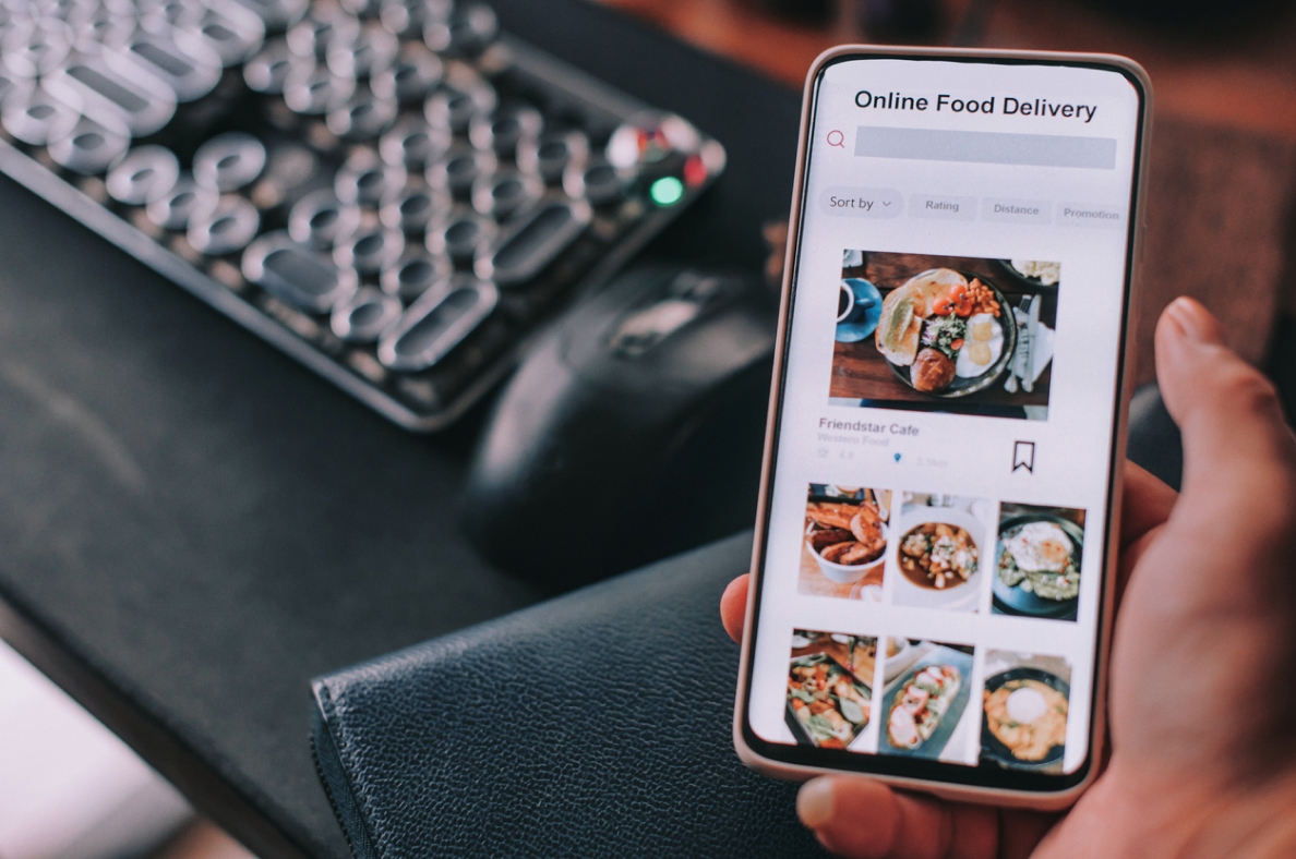 A man holds his smartphone while browsing a food delivery app. 