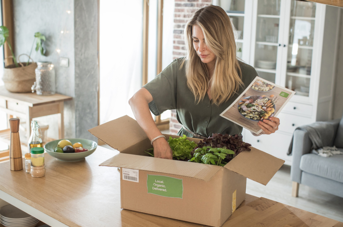 A woman unboxes a meal kit that was delivered to her home. 