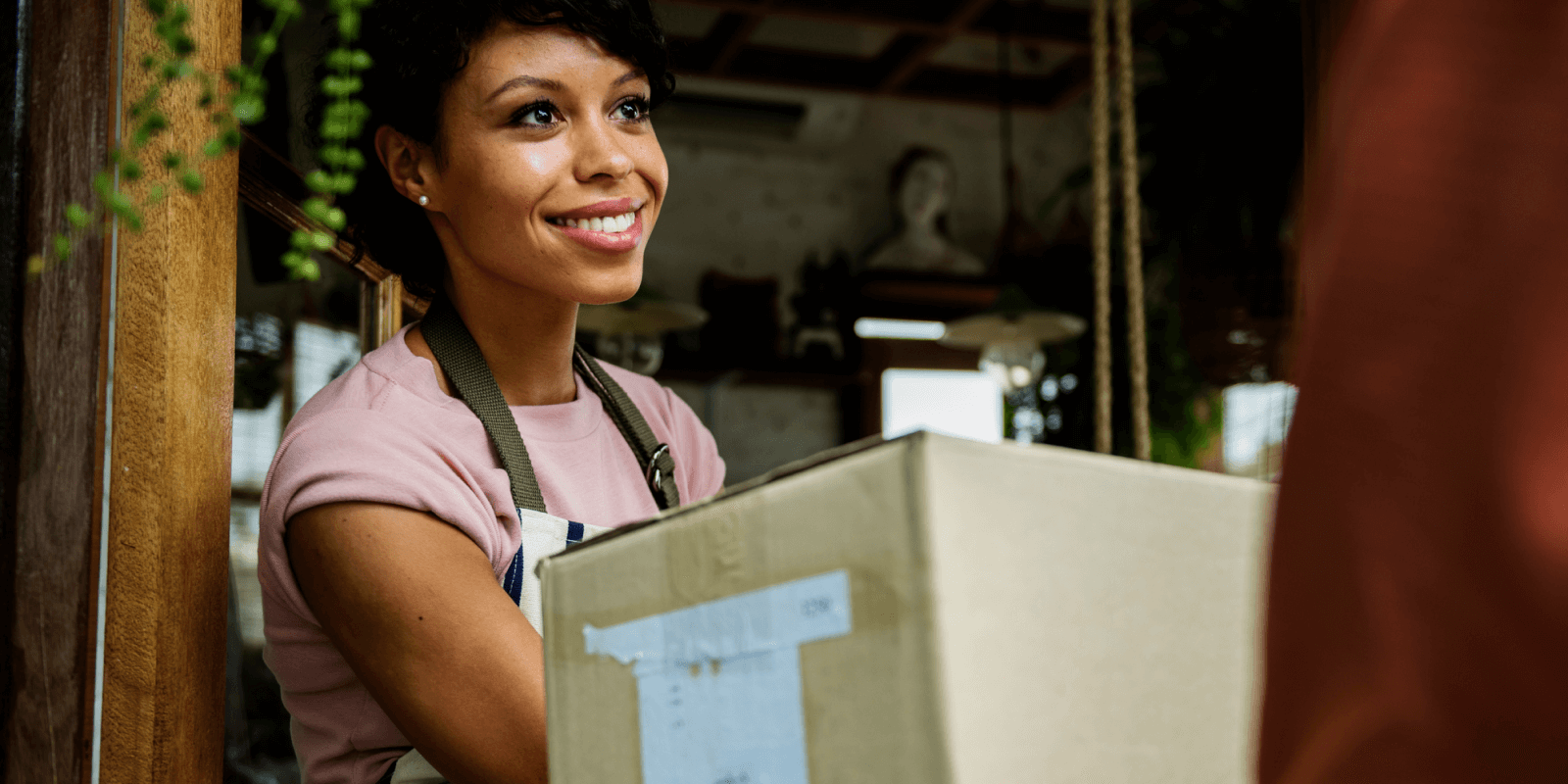A smiling business owner gives a package to a delivery agent. 