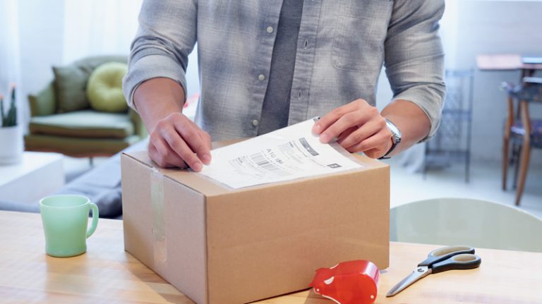 A man applies a return shipping label to a box.